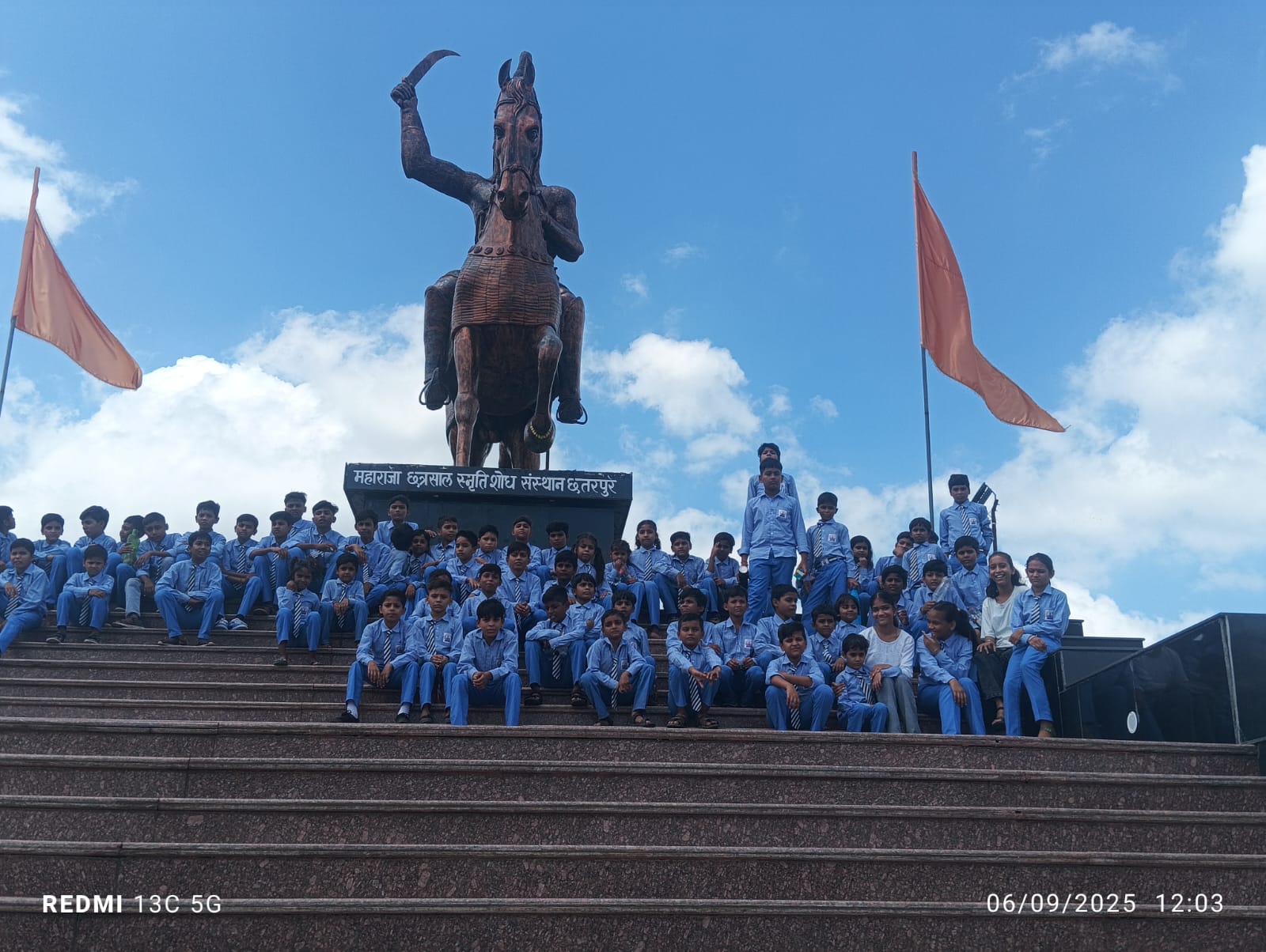 Students on an educational trip, seated below the Maharaja Chhatrasal statue in Chhatarpur